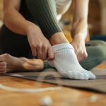 closeup-sportswoman-wearing-white-socks-while-preparing-workout-home_637285-2992