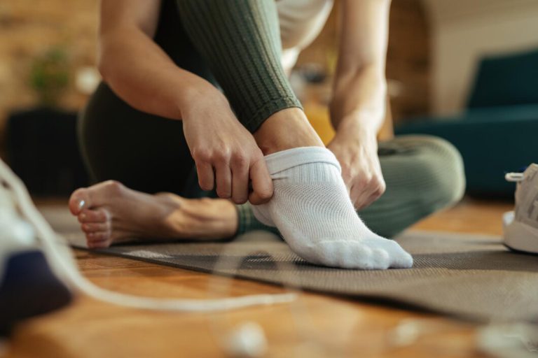 closeup-sportswoman-wearing-white-socks-while-preparing-workout-home_637285-2992